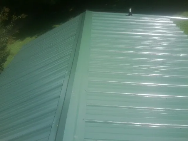 New green metal panels meeting at the ridge of a roof — Flat Roof Repair work by our crew in La Valle
