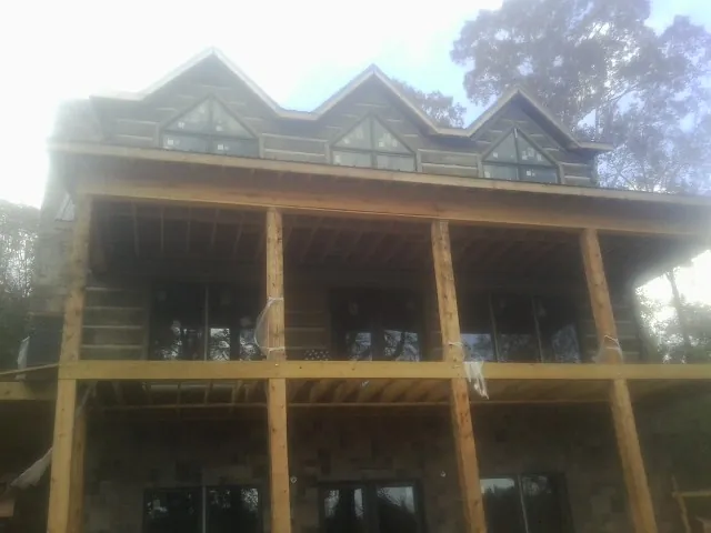 Dormers and porch framing on a large log home under construction — Roof Coating work by our crew in La Valle