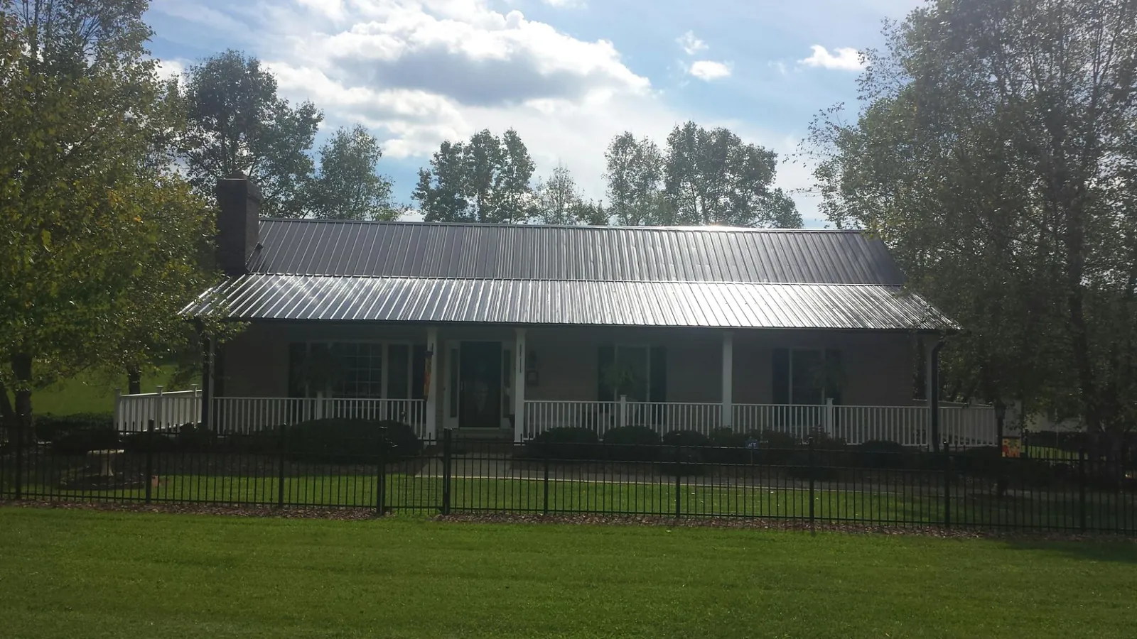 Gray metal roof on a brick ranch with a full width front porch — Gutter Guard Installation work by our crew in La Valle