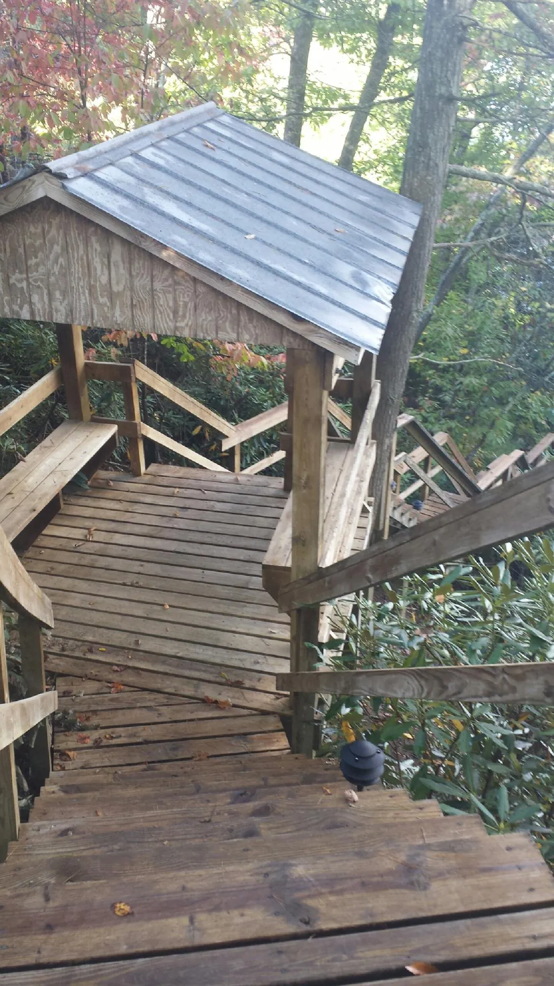 Metal roofed shelter over wooden steps on a wooded walkway — Skylight Repair & Installation work by our crew in La Valle