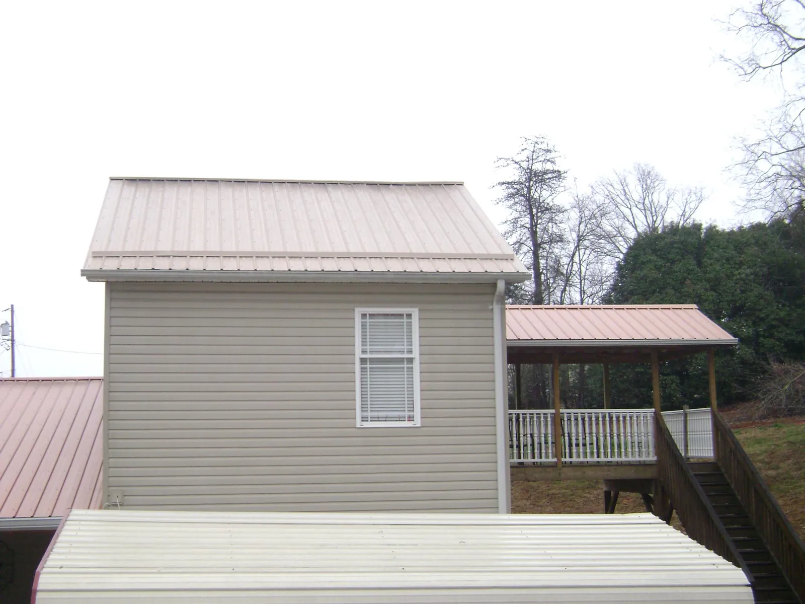 Tan metal roofs on a two story addition and attached porch, from a Roof Replacement job in La Valle